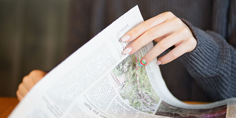 Eine junge Frau blättert eine Zeitung um